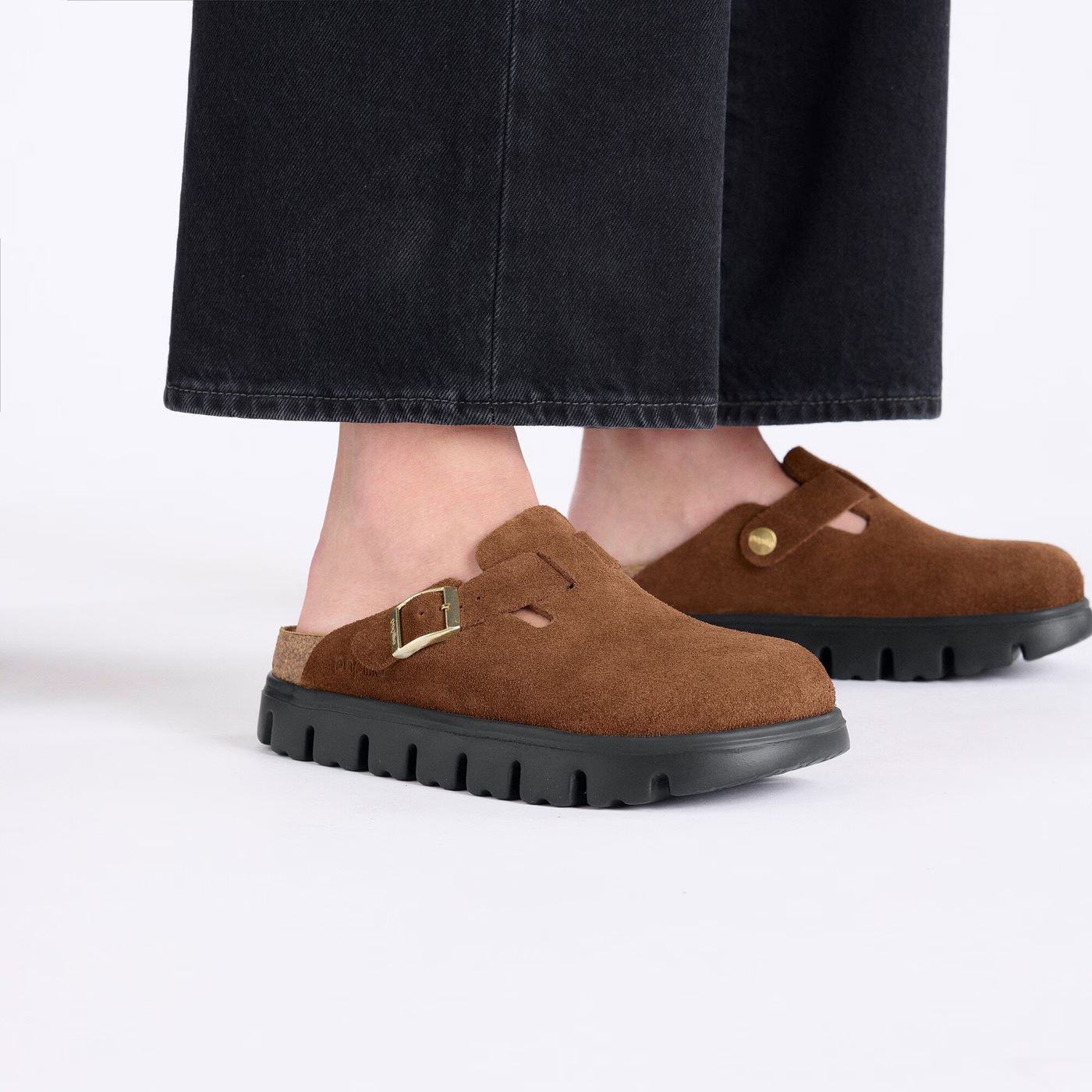 Close-up of Birkenstock Boston Chunky clogs in dark tea suede styled with black wide-leg pants.