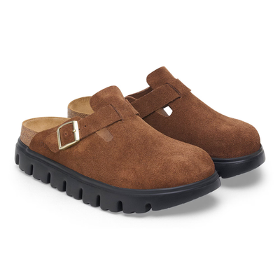 Side view of a pair of Birkenstock Boston Chunky clog in dark tea suede with a gold buckle and a black chunky sole for a bold look