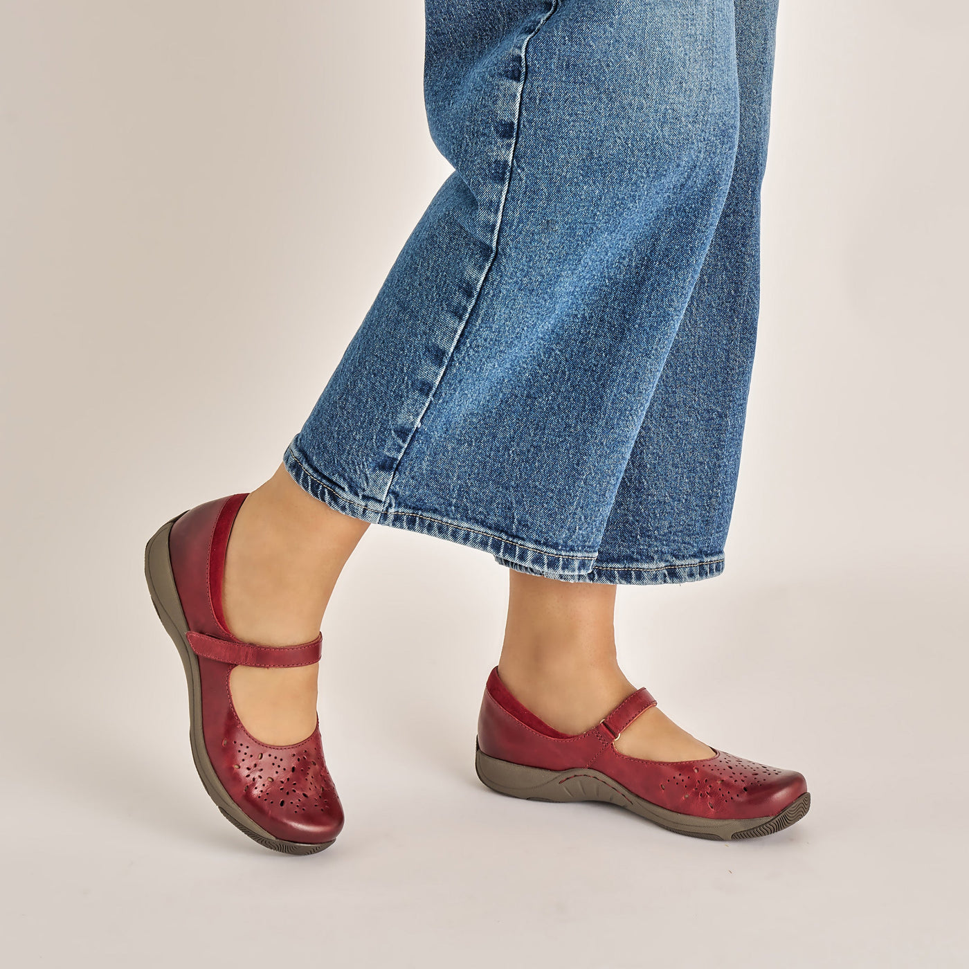 Women’s Dansko Stacy red leather Mary Jane featuring adjustable strap, cushioned EVA arch support, and slip-resistant outsole for stability.