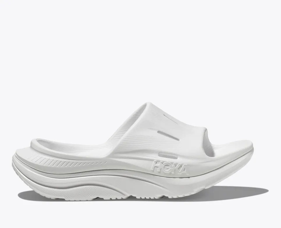 HOKA ORA Slide 3 in white, featuring ventilated air flow channels, a dual-density sugarcane EVA midsole, and an injection-molded outsole for lightweight recovery and all-day comfort.