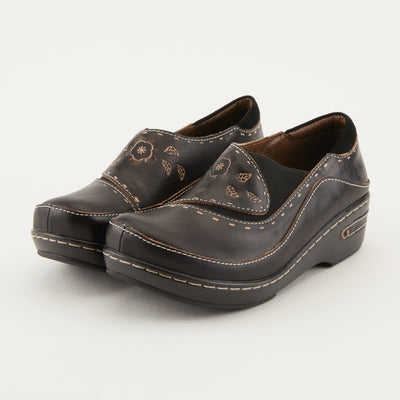 Black L’Artiste Burbank slip-on clogs featuring hand-painted floral leather, elastic side inlay, and durable platform sole.