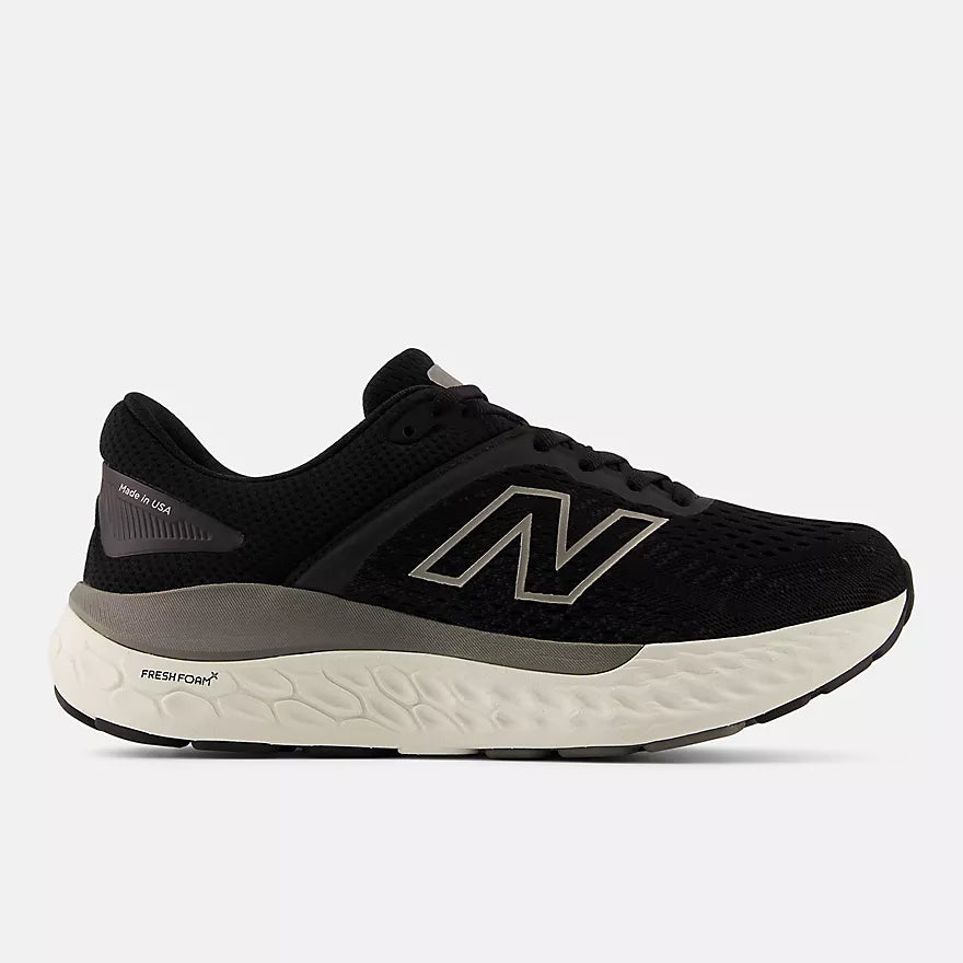 New Balance black and gray running shoe with Fresh Foam X midsole and ROLLBAR stability system, featuring engineered knit upper and cushioned sole for all-day comfort and support.