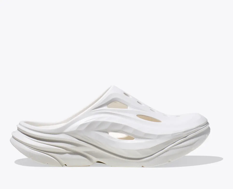 HOKA Ora Recovery Mule in white color, featuring a sculpted EVA design with vented airflow channels, a sugarcane EVA midsole, and a futuristic slip-on silhouette for enhanced breathability and comfort.