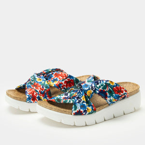 Pair of colorful knotted slide sandals with a hidden hook-and-loop closure for an adjustable fit, featuring a cork footbed and a lightweight white heritage outsole for comfort and support.