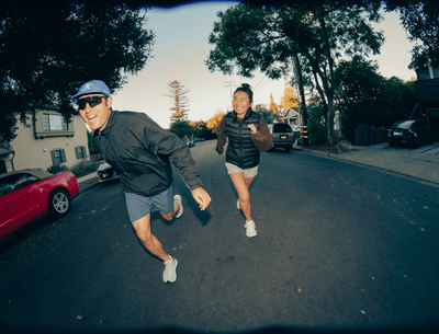 Two runners smiling as they jog wearing cream rose running shoes