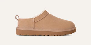 Sand suede UGG Classic Micro boot, low profile with sheepskin lining at collar, rear pull tab, and treaded sugarcane EVA sole; minimalist studio background