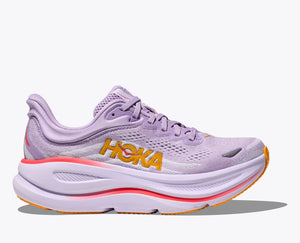 Side view of a lavender HOKA running shoe with breathable mesh uppers, yellow HOKA logo, and orange accents on the sole and heel, featuring a cushioned midsole for added support.