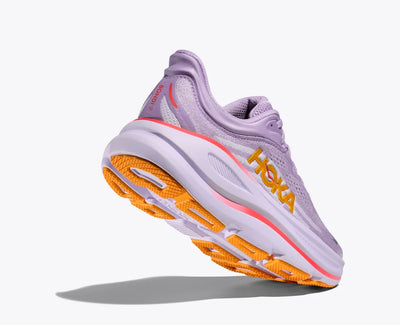 Angle view of a lavender HOKA running shoe with breathable mesh uppers, yellow HOKA logo, and orange accents on the sole and heel, featuring a cushioned midsole for added support.