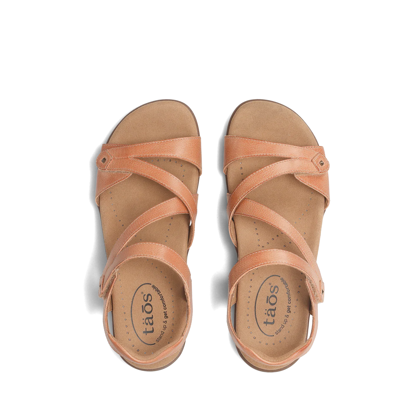 Top view of a pair of natural beige Taos sandals featuring crisscrossing adjustable straps and a cushioned, perforated footbed.