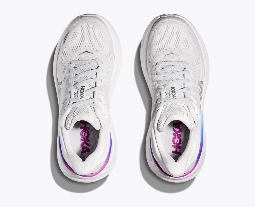 Top-down view of a pair of white HOKA running shoes with breathable mesh uppers, purple and blue gradient detailing on the heels, and the HOKA logo visible on the insoles.