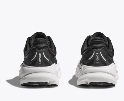 Back view of a black HOKA running shoe with breathable mesh uppers, white HOKA logo, and a thick white cushioned sole designed for comfort and support.