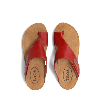 Top view of a pair of red Taos sandals featuring a slip-on design with a soft suede footbed and subtle stitching details.