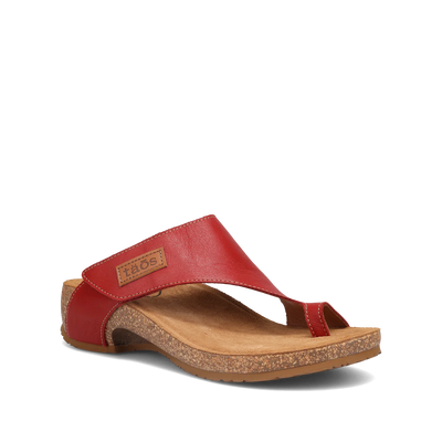 Side view of a pair of red Taos sandals featuring a slip-on design with a soft suede footbed and subtle stitching details.